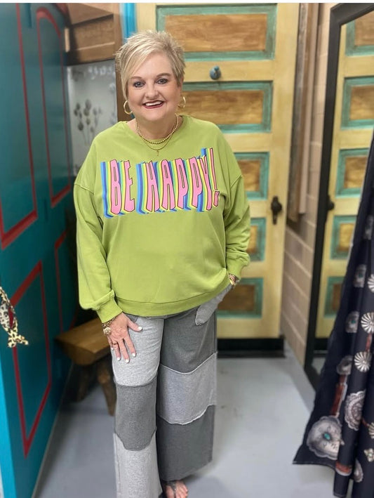 woman wearing green be happy sweatshirt with pink and blue text