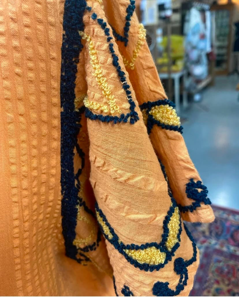 Close up of embroidered sleeve detail on orange Darcy Top.