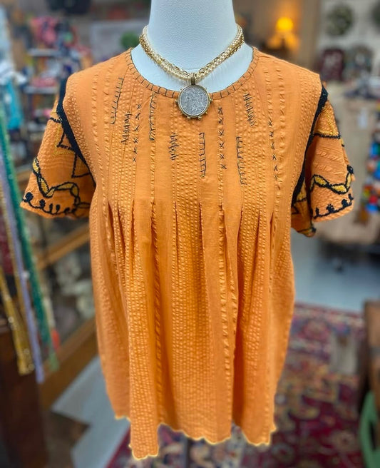Front view of orange cotton Darcy Top with embroidered details displayed on mannequin.