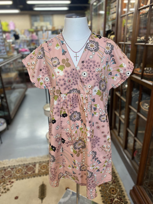 pink dress with multicolor floral print and v-neckline on mannequin in boutique setting